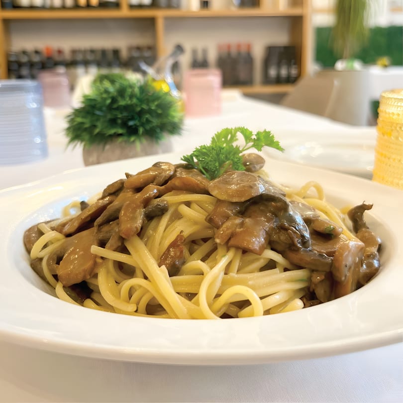 Linguine pasta with creamy mushroom sauce and fresh parsley on a white plate.